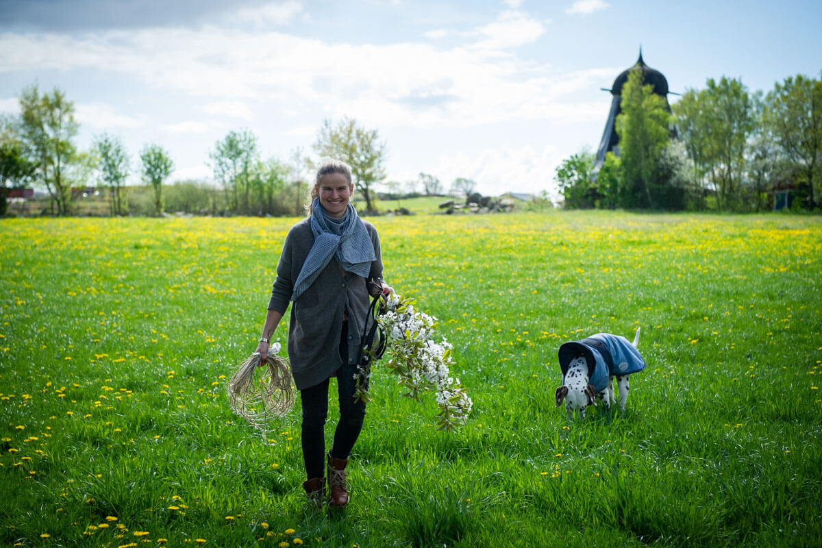 kvinna går över äng med blommor och sin hund