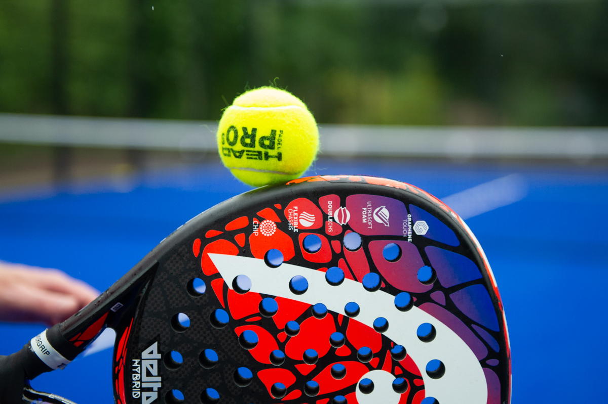 rött padelrack med gul boll på kanten